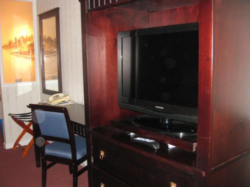a television in a wooden entertainment center with a chair at Glynmill Inn in Corner Brook