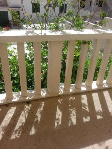 a white fence with its shadows on the ground at Apartments Jerica in Bol