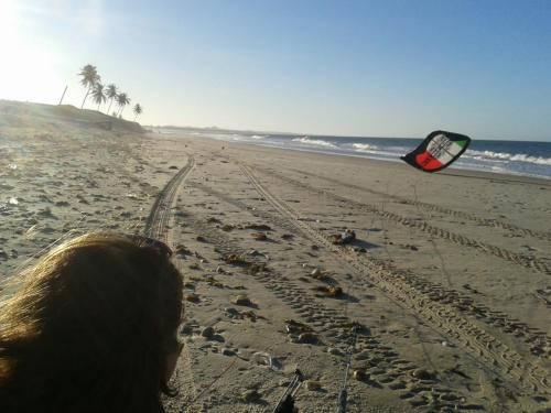 a woman is flying a kite on the beach at Pousada Brasita in Cumbuco