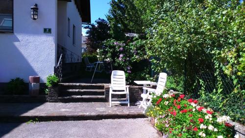 two white chairs sitting in front of a house with flowers at Haus Ruf in Windischgarsten