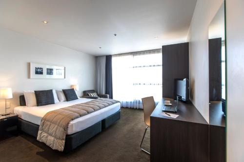 Pokój hotelowy z łóżkiem i biurkiem z telewizorem w obiekcie Quest Parnell Serviced Apartments w Auckland