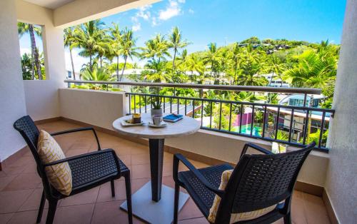 a balcony with a table and chairs and palm trees at Port Douglas Peninsula Boutique Hotel - Adults Only Haven in Port Douglas