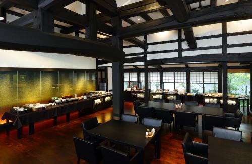 a restaurant with black tables and chairs and windows at Yamaha Resort Katsuragi Kitanomaru in Fukuroi
