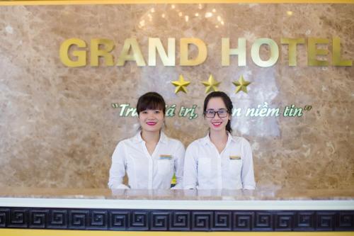 two women standing behind a counter at a grand hotel at Grand Hotel in Hòa Bình