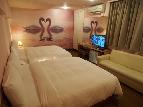 a hotel room with two beds and a couch and a television at Day Chen Hotel in Yilan City