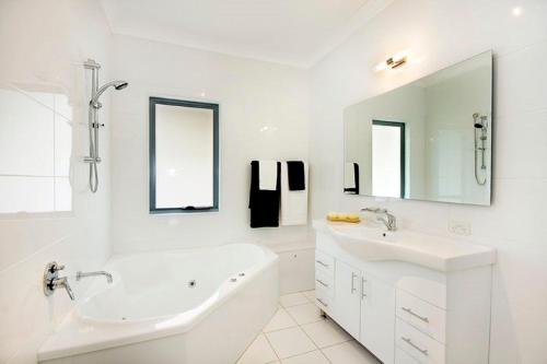 a white bathroom with a tub and a sink at The Beach Townhouse in Hawks Nest