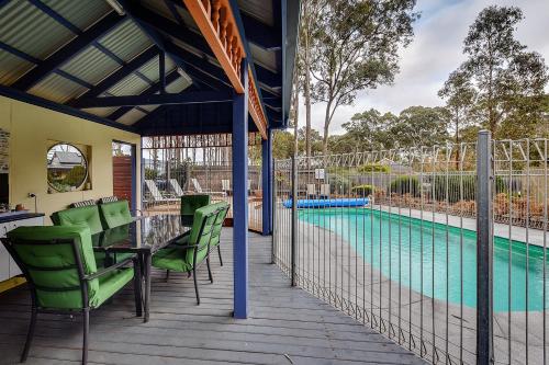a deck with a table and chairs and a swimming pool at Waverley House Cottages in Lakes Entrance