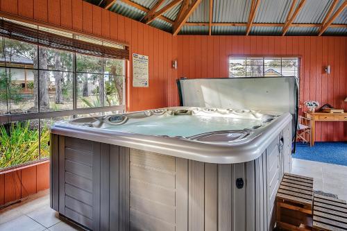 a large hot tub in a room with windows at Waverley House Cottages in Lakes Entrance
