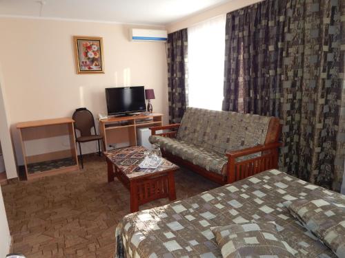 a hotel room with a bed and a couch and a tv at Гостиница ИЛЕК in Aktobe
