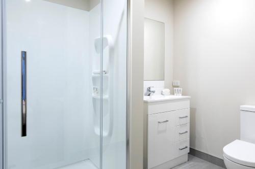 a bathroom with a shower and a toilet and a sink at Quest Whangarei in Whangarei