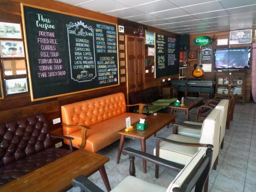 a restaurant with couches and tables and a chalkboard at Noom Guesthouse in Lop Buri