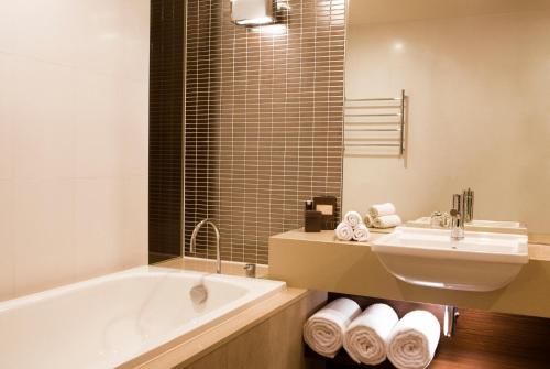 a bathroom with a tub, sink and mirror at Pullman Sydney Olympic Park in Sydney