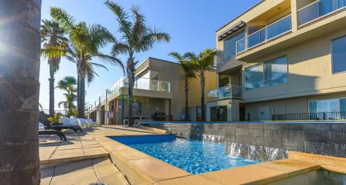 a swimming pool in front of a house with palm trees at The Bluff Resort Apartments in Encounter Bay