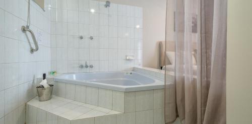 eine Badewanne in einem weiß gefliesten Bad in der Unterkunft Mandala Ace Albany Hotel in Albany
