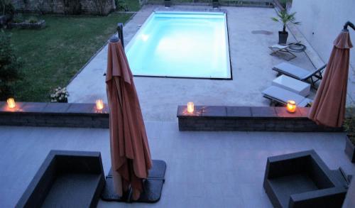two umbrellas and candles next to a swimming pool at La Houblonniere in Beire-le-Châtel