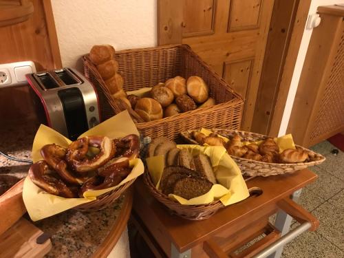 a bunch of baskets of bread and pastries on a counter at Landhaus Kössel in Füssen