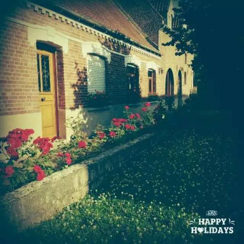 a sign that says happy holidays next to a house with flowers at Le moulin de Cohem in Blaringhem