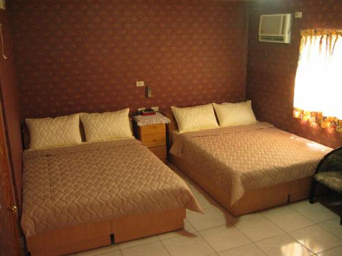 una habitación de hotel con 2 camas y una silla en 宏瑞民宿, en Beigan