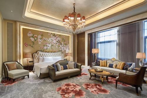 a bedroom with a bed and a couch and chairs at Wanda Vista Harbin in Harbin