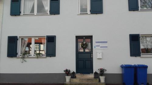 a white house with blue shutters and a door at Kleines Stadthaus Grünberg in Grünberg