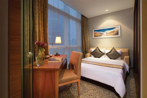 a hotel room with a bed, desk, chair and a lamp at Oakwood Premier Cozmo Jakarta in Jakarta