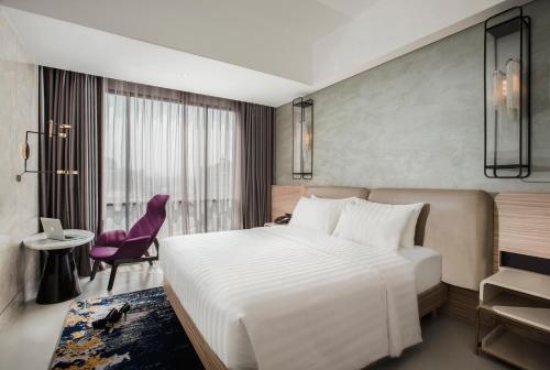 a bedroom with a large white bed and a purple chair at Mercure Bandung City Centre in Bandung