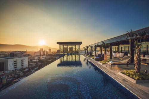 a swimming pool on top of a building with a sunset at Mercure Bandung City Centre in Bandung