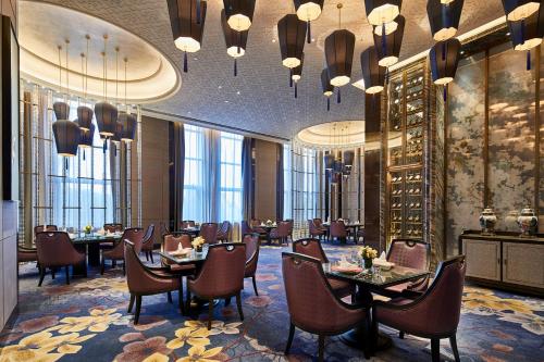 a dining room with tables and chairs and chandeliers at Wanda Vista Harbin in Harbin
