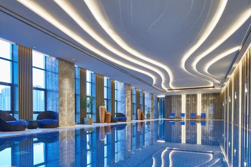 a swimming pool in a hotel lobby with windows at Wanda Vista Harbin in Harbin