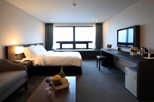 a hotel room with a bed and a desk and a television at Best Western Jeju Hotel in Jeju