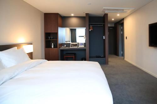 a bedroom with a large white bed and a desk at Best Western Jeju Hotel in Jeju