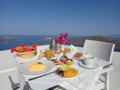 a table with breakfast foods and drinks on a balcony at Langas Villas in Imerovigli