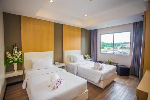 una camera d'albergo con due letti e una finestra di New Travel Lodge Hotel a Chanthaburi