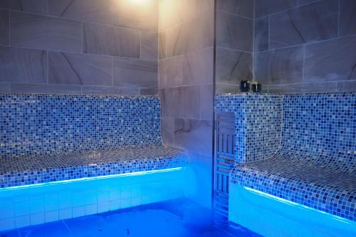 a bathroom with blue tiled walls and a shower at New Travel Lodge Hotel in Chanthaburi