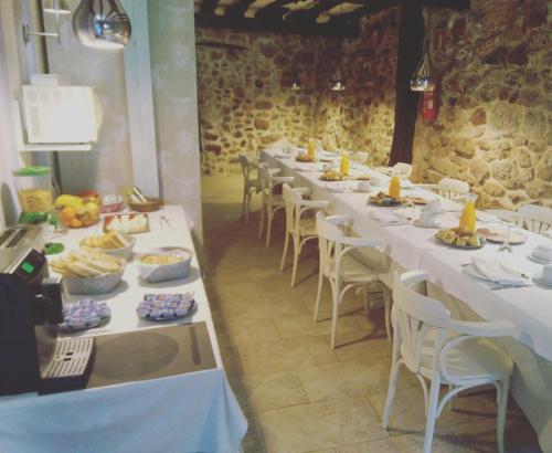 PámanesPosada La Corralada的一张长桌子,上面有白色的桌子和椅子,上面有食物