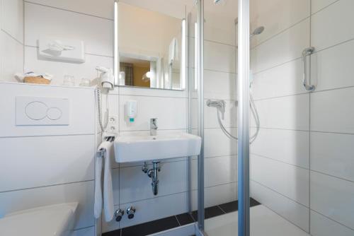 ein weißes Badezimmer mit Waschbecken und Dusche in der Unterkunft Atlantic Hotel Garni in Wangerooge