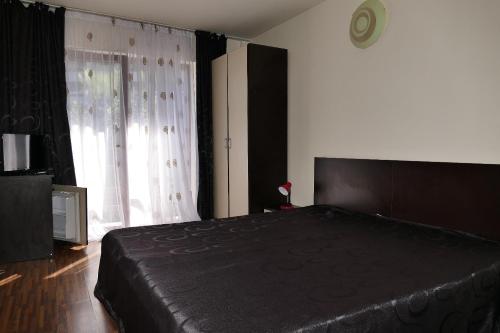 1 dormitorio con cama negra y ventana grande en Pensiunea Pinul Negru, en Băile Herculane