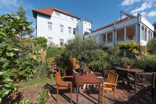 a patio with tables and chairs and a building at Atlantic Hotel Garni in Wangerooge