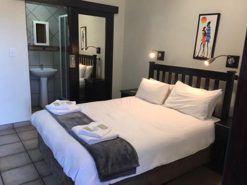 ein Schlafzimmer mit einem Bett mit zwei Handtüchern darauf in der Unterkunft Towers Lodge in Boksburg