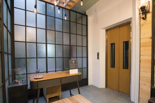 a room with a wooden desk in front of a glass wall at Atreeium in Tainan