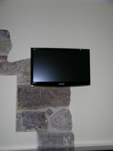 a flat screen tv hanging on a stone wall at Domus Lilio in Petralia Sottana