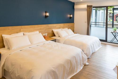 two beds in a hotel room with white sheets at Atreeium in Tainan