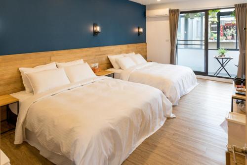 a bedroom with two beds with white sheets at Atreeium in Tainan
