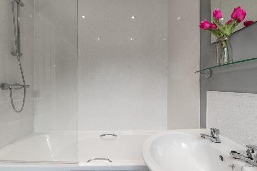 a bathroom with a sink and a vase of pink flowers at Bishop's Rest in Bishop Auckland