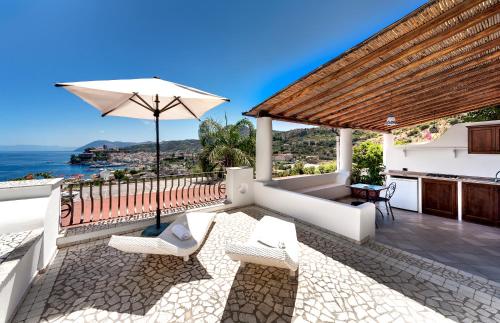 a patio with chairs and an umbrella and the ocean at Hotel Villa Enrica - Aeolian Charme in Lipari