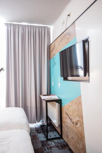 a bedroom with a bed and a tv on a wall at The Originals Access, Hôtel Clermont-Ferrand Nord in Châteaugay