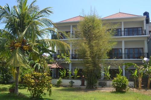 a building with palm trees in front of it at Master Homestay in Amed