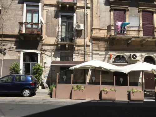 un coche aparcado frente a un restaurante con sombrilla en Casa vacanza Civita Catania Centro, en Catania