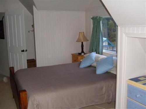 um quarto com uma cama com almofadas azuis e uma janela em Beachs 'n Greens em Greens Beach