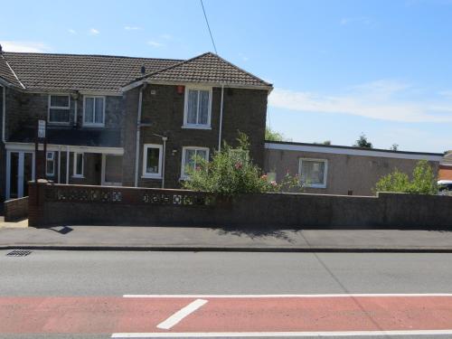 a house on the side of a street with a road at Four seasons Guest House in Pembrey